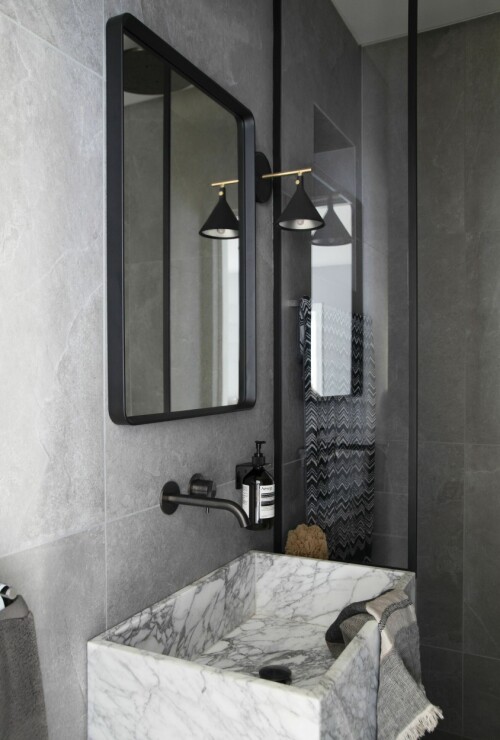Gjestebadet i første etasje er inspirert av Menus showroom og boutiquehotell The Audo i København. Servanten i arabescomarmor er spesialdesignet for badet. Den veggmonterte kranen er fra Gessi, speilet og lampen fra Menu. 