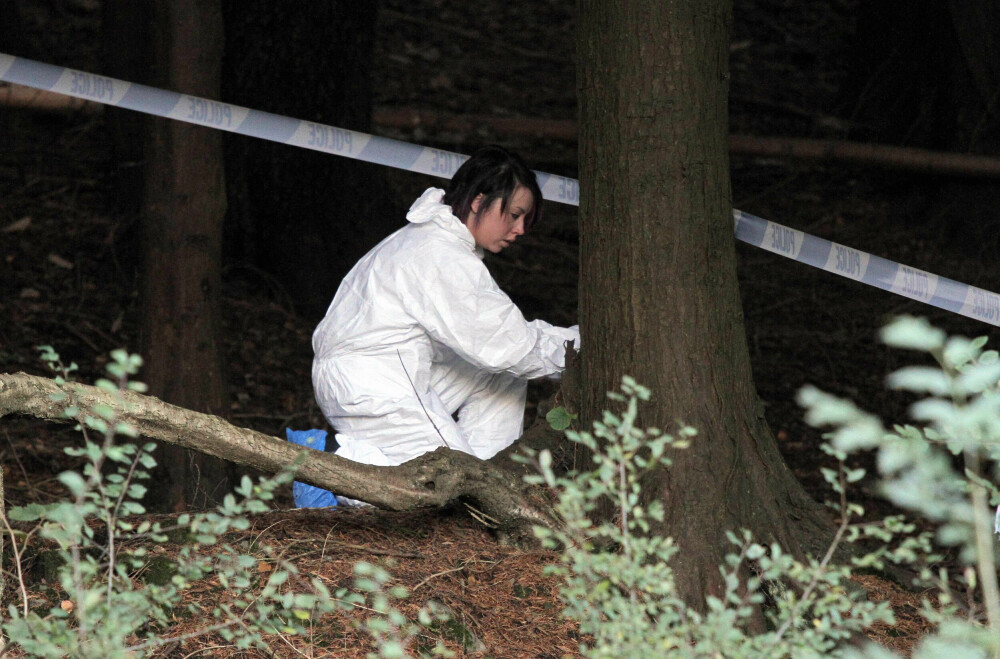 <b>SLÅTT I HJEL:</b> En krimtekniker gransker åstedet i den mørke skogen der liket av Rebecca Aylward (15) ble funnet. 