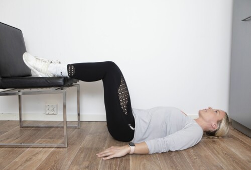 <b>ØVELSE 4:
Setehev. </b>Ligg på ryggen med strake armer i gulvet og bena på en stol. Ha bøyde hofter og knær. Stram magen og løft opp setet til kun skuldrene har kontakt med gulvet og du har en strak kropp mellom skuldre og knær. Hold noen sekunder og senk rolig tilbake til utgangsstilling. Repetisjoner: 10 x 3 Muskler som trenes: Bakside lår, sete og korsrygg