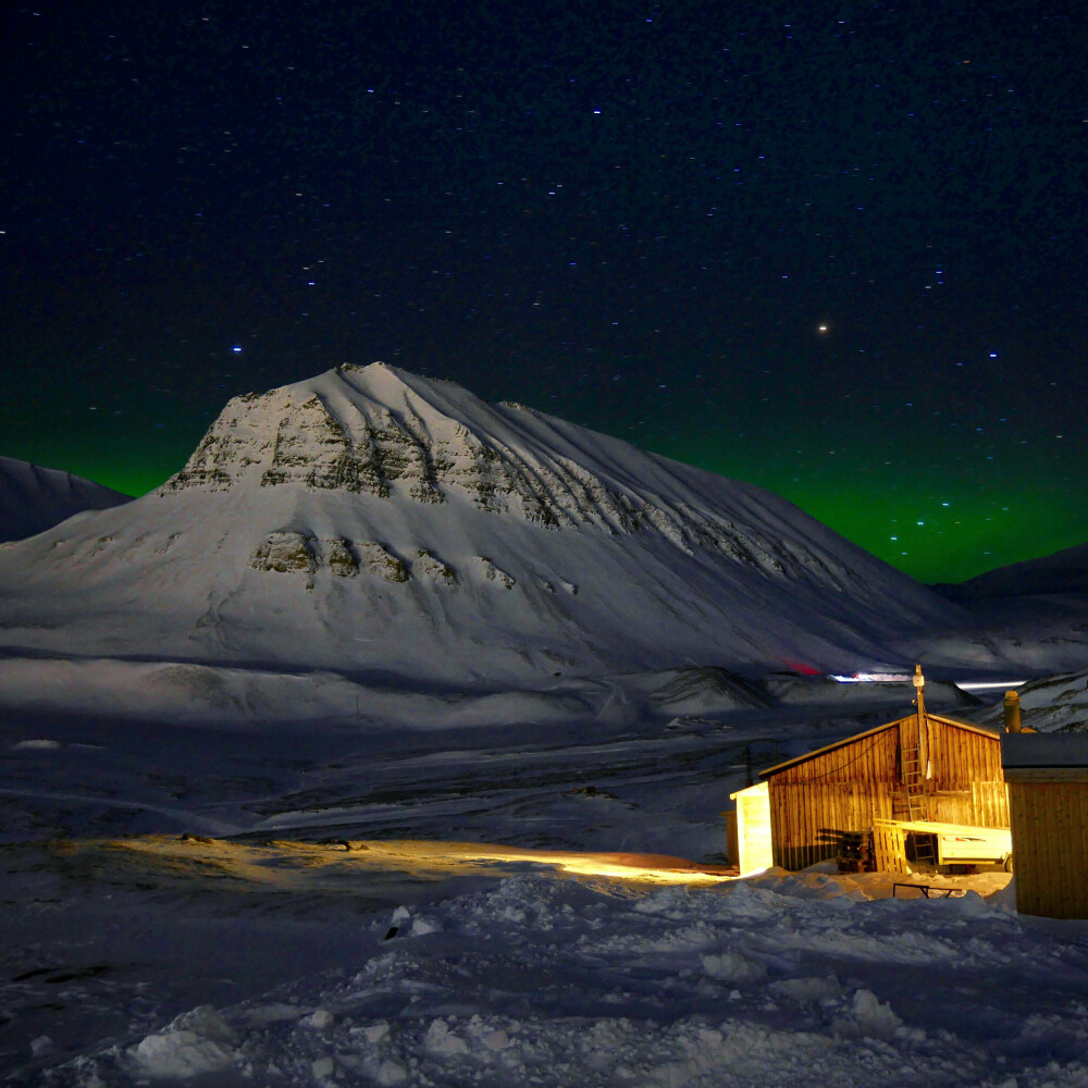 Dette bildet er tatt på Svalbard, den lyse himmelen bak fjellet skyldes lys fra bebyggelse.