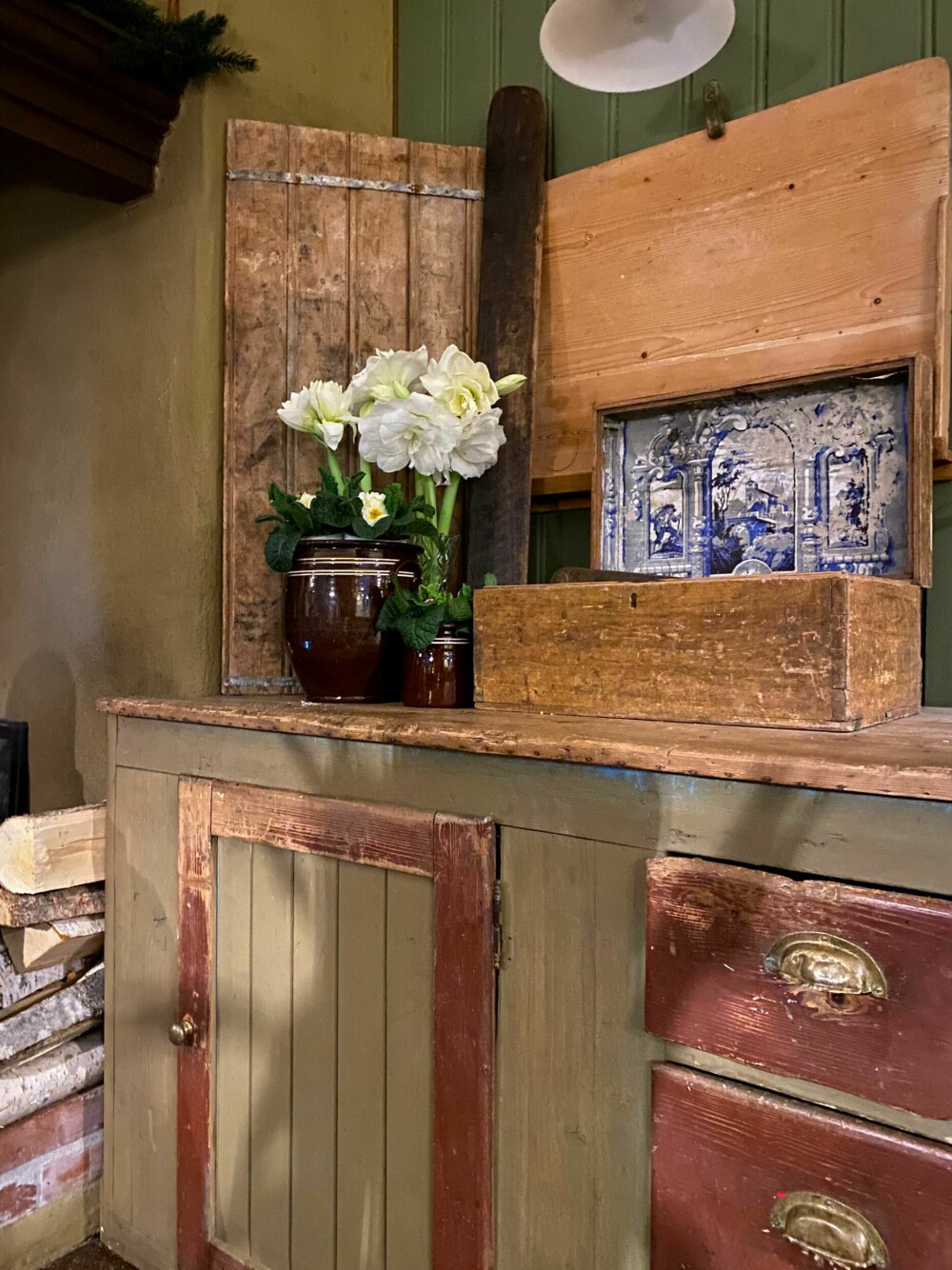 KJØKKENBENK: Gamle kjøkkenbenker med all sin patina er ikke nødvendigvis veldig praktisk, men du verden så vakkert! Her er den gammeldagse stilen understreket av den fine bakstefjøla som henger på veggen.