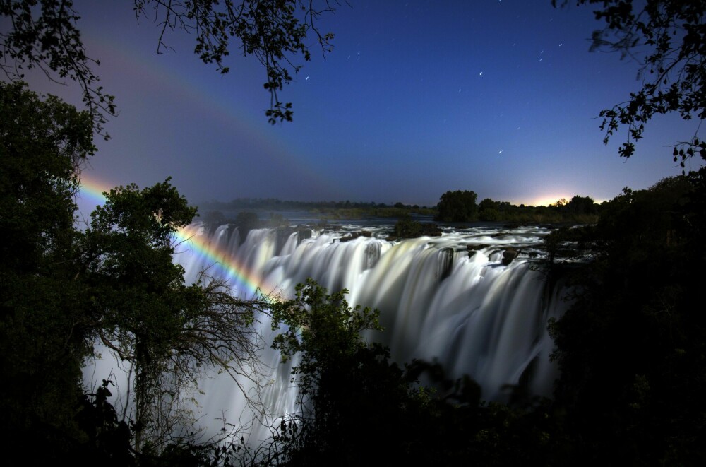<b>MÅNE-REGNBUE:</b> Dette fenomenet, som også kalles «lunar ­regnbue», blir skapt av lys reflektert av månen i stedet for direkte sollys. Den er et fenomen som ligner på det som skjer med den vanlige regnbuen, men om natten. Måneregnbuen på bildet er fra Victoriafallene i Zambia i Afrika. Den har likhetstrekk med den vanlige regnbuen, bare at den er et nattens fenomen og er en sjelden forekomst fordi det må en spesiell lysstyrke og en bestemt avstand fra månen til. Grunnen til at den er mindre lyssterk enn en vanlig regnbue, er at månen sender ut mindre lys enn solen.