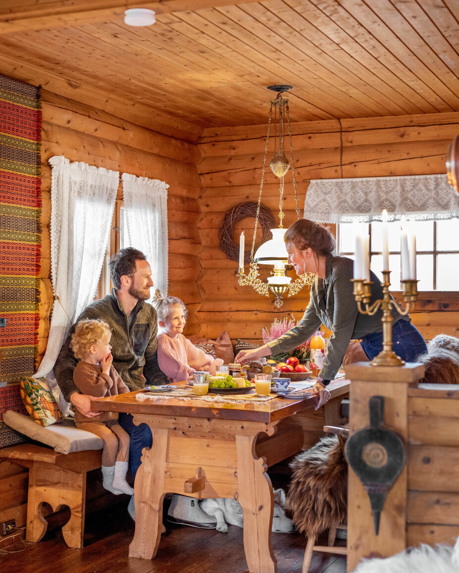 SAMLE SEG: Det er tid for lunsj på hytta, og familien liker å samle seg rundt bordet. Budalstolene er arvegods, spisebordet og benkene sto her fra før, mens taklampen er kjøpt via Finn.