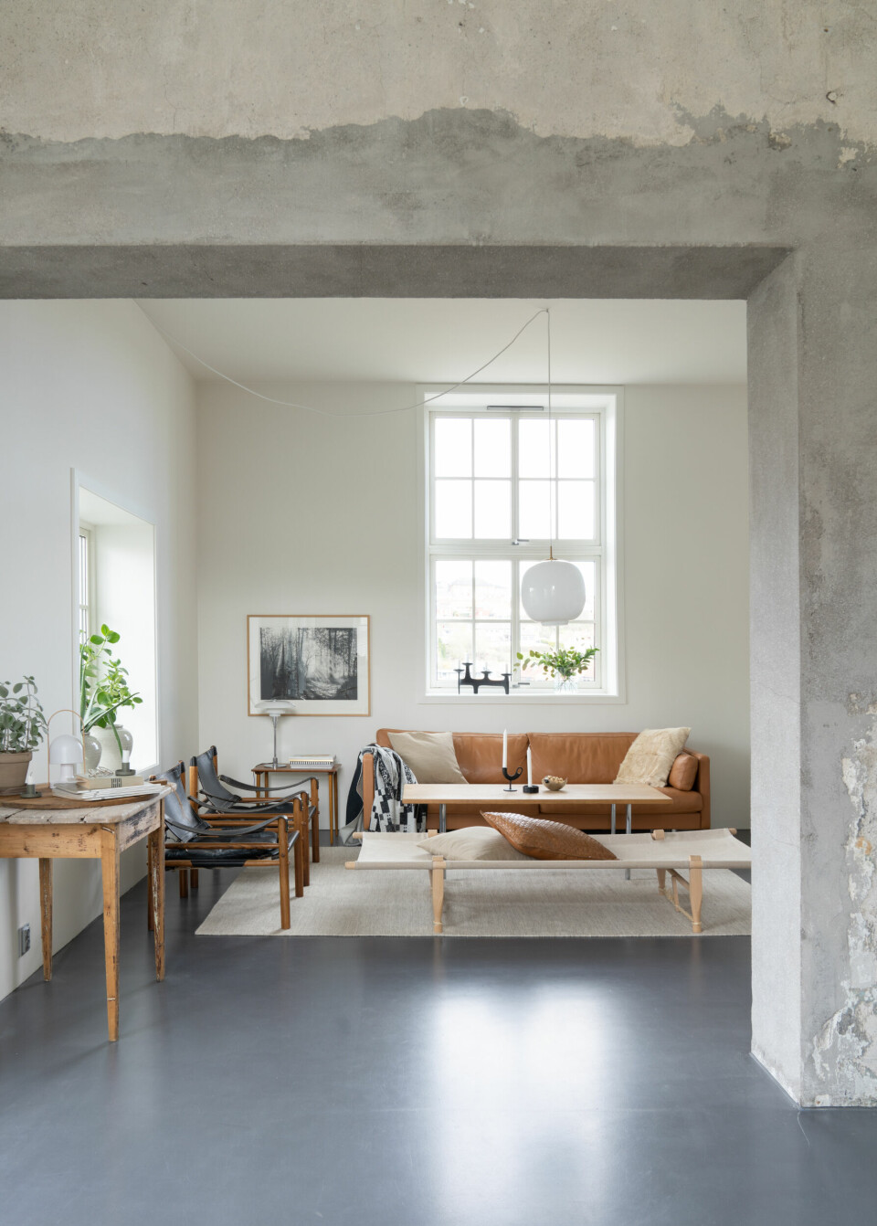 I stuen er vegger og tak malt i fargen Letthet fra Jotun. Designgulvet G80 med lakk 1 fra Weber gir rommet det rå og industrielle preget. Sofaen Saxo er fra Møbelgården i Skien, og Wegner-bordet er kjøpt brukt. Daydsengen fra Skovshoved er kjøpt hos Mitt Hjem i Sandefjord, og pendellampen Radiohus er fra Louis Poulsen.