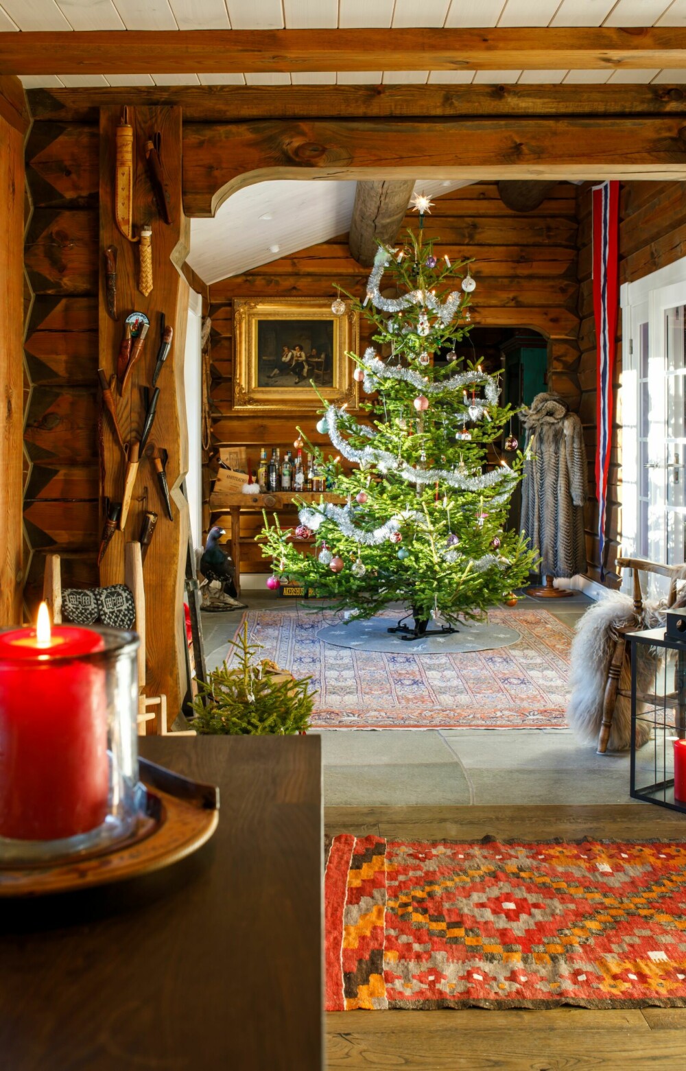 JULETRE: Juletreet funkler i den lave vintersola som gjennomlyser hytta. Fargerike kelimtepper gir en lunhet til hytta, og er en fin kontrast til gløden i tømmeret.