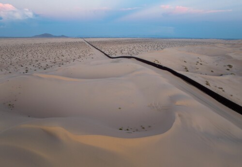 <b>GRENSE I SANDDYNENE:</b> Dette er grensegjerdet mellom USA og Mexico gjennom Californias Imperial Sand Dunes. Grensen har fått kallenavnet flytende gjerde fordi det sitter på toppen av sanddynene og beveger seg med den skiftende sanden. 