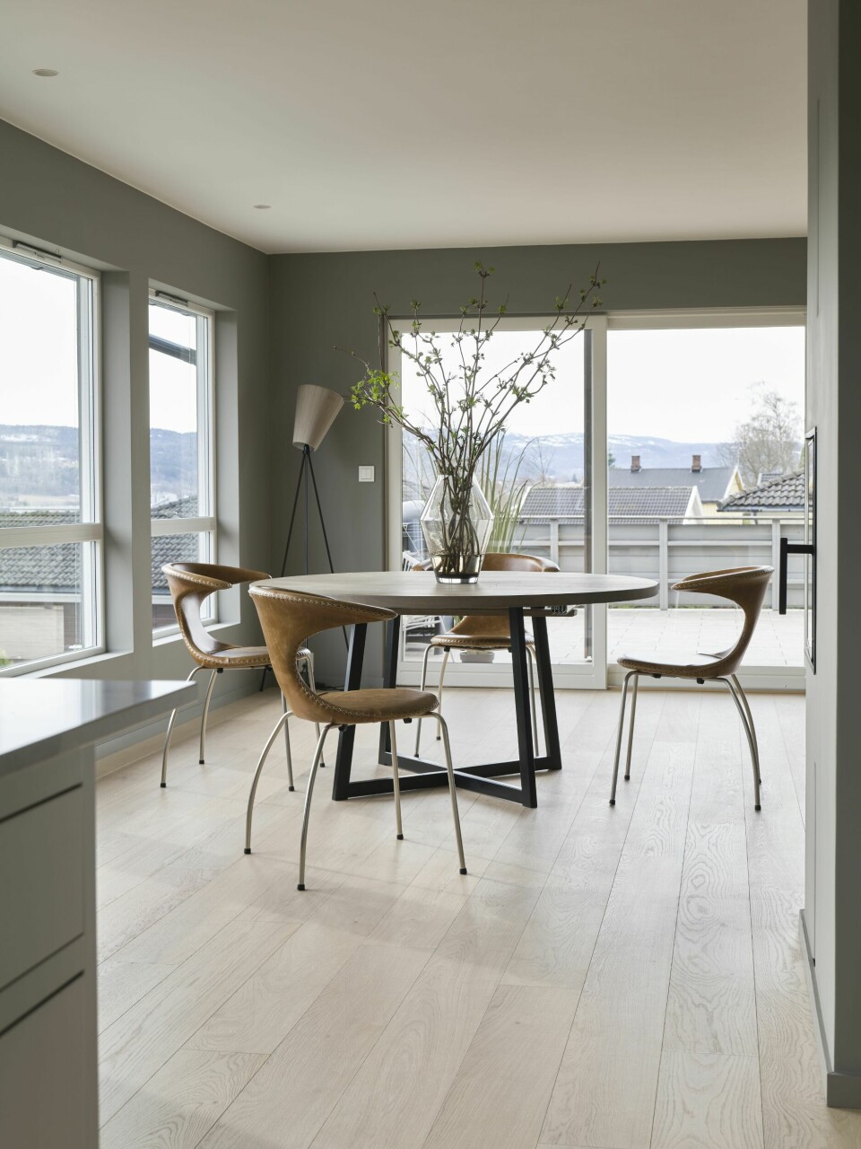 De klassiske vinduene i spisestuen ble byttet ut med fire skyvedører i glass. Nå bader allrommet i lys, og familien kan nyte utsikten på en helt annen måte enn tidligere. Spisebordet fra Woodstory og spisestolene Flair fra Danform er kjøpt hos Møbelringen i Hokksund, i likhet med vasen på bordet. I hjørnet står gulvlampen Oslo Wood fra Northern.