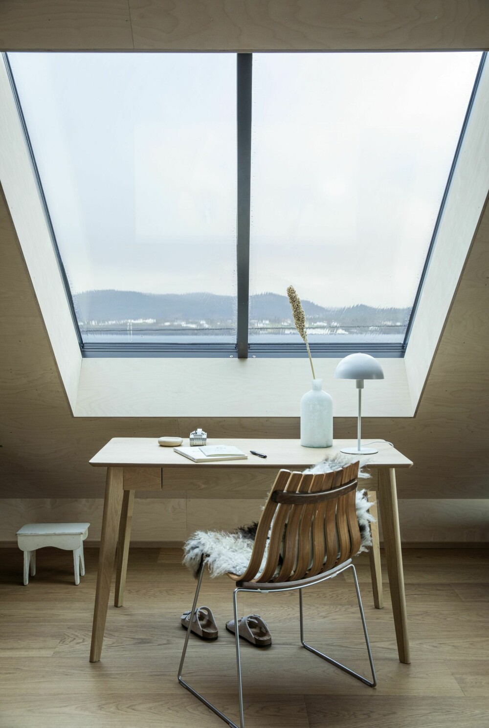 Fra arbeidsplassen sin har Gro Linn spektakulær utsikt over Sunnmørsalpene og fjorden. Skrivebordet er fra Jysk. Stolen, Hans Brattruds klassiker Scandia fra 1957, regnes som et av høydepunktene i norsk og skandinavisk designhistorie.
