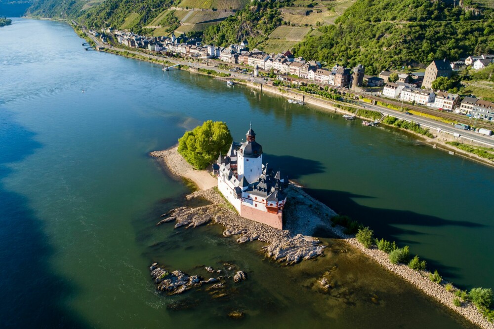 <b>LANGS RHINEN:</b> Reisen med MittelrheinBahn er pur idyll. Her er Rhinen og slottet Pfalzgrafen­stein på Falkenau-øya på den ene siden av sporet og idylliske Kaub på den andre.