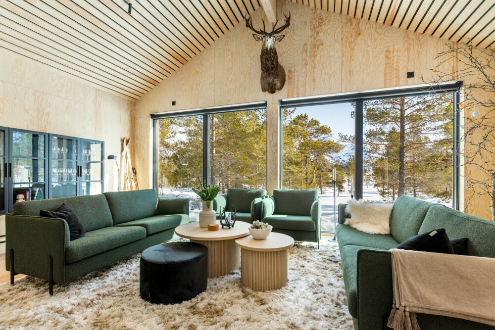 STORE VINDUER: De store vinduene tar naturen inn i stuen. Fra sofaen får man en følelse av å sitte midt i skisporet. Møblene er fra Fagmøbler.