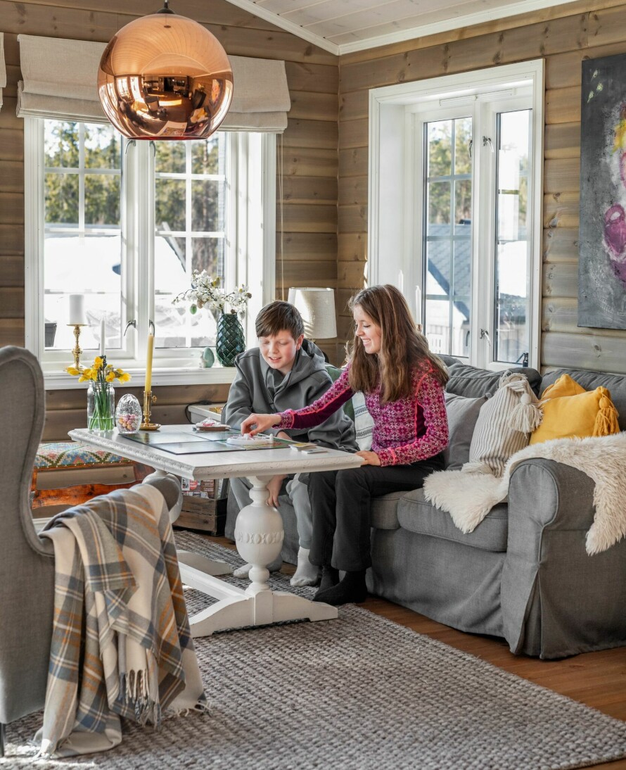 HYTTEKOS: Noah og Dina koser seg med brettspill i stuekroken. Taklampen fra Tom Dixon er kjøpt brukt, mens sofaen og stolene er fra Ikea. Bordet ble kjøpt på Vollywood på Vollen for mange år siden.