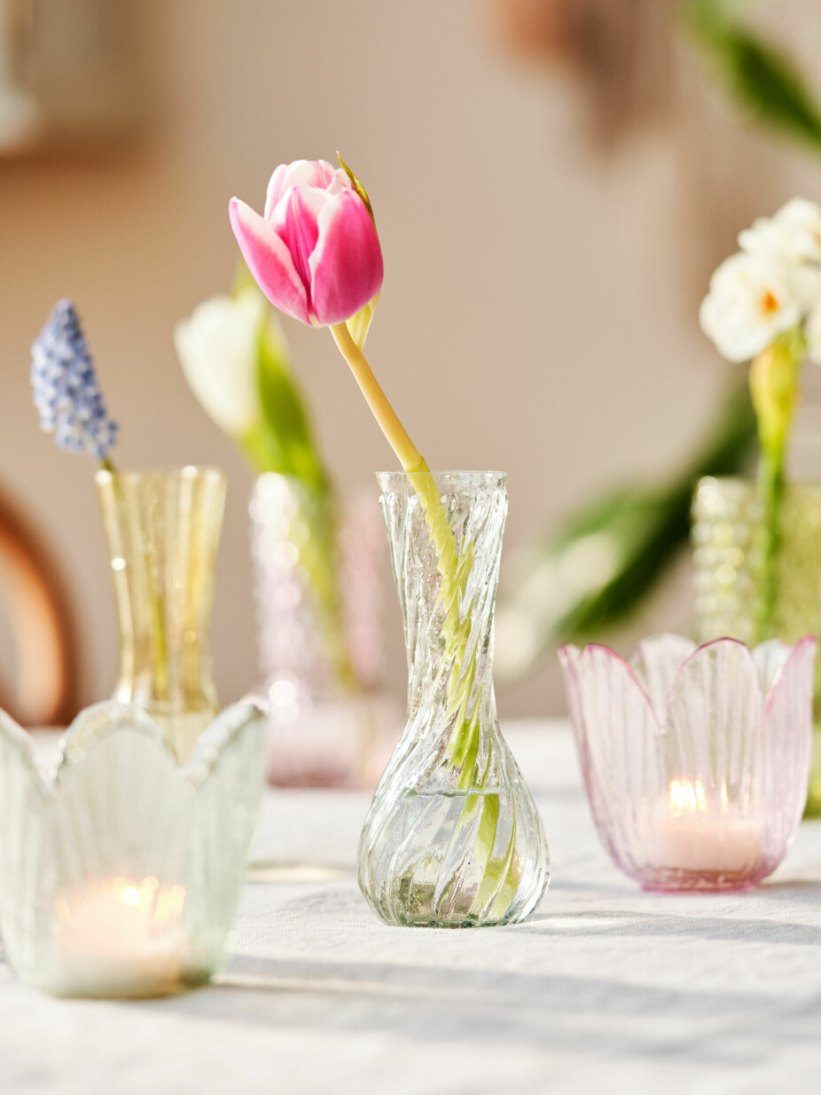 Sett enkeltblomster i små vaser eller glass og spre dem rundt på bordet sammen med telys. Så enkelt, så lekkert.