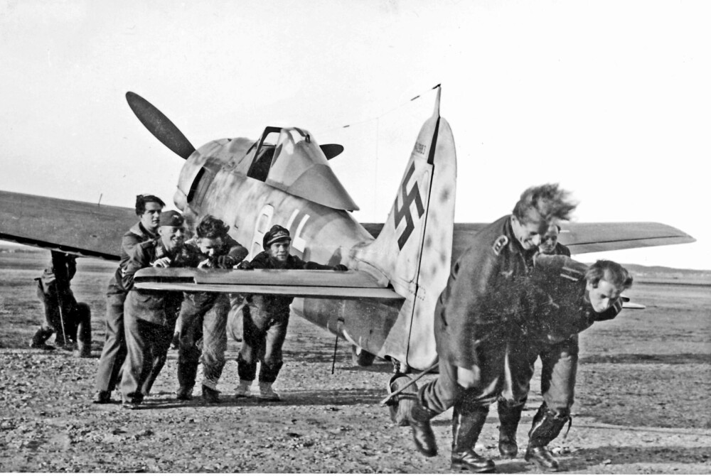 <b>DAGLIGLIV PÅ BASEN:</b> En av Focke Wulf 190-jagerflyene blir rutinemessig buksert inn til beskyttelsesrommet etter tokt. Napp bakerst til venstre.
