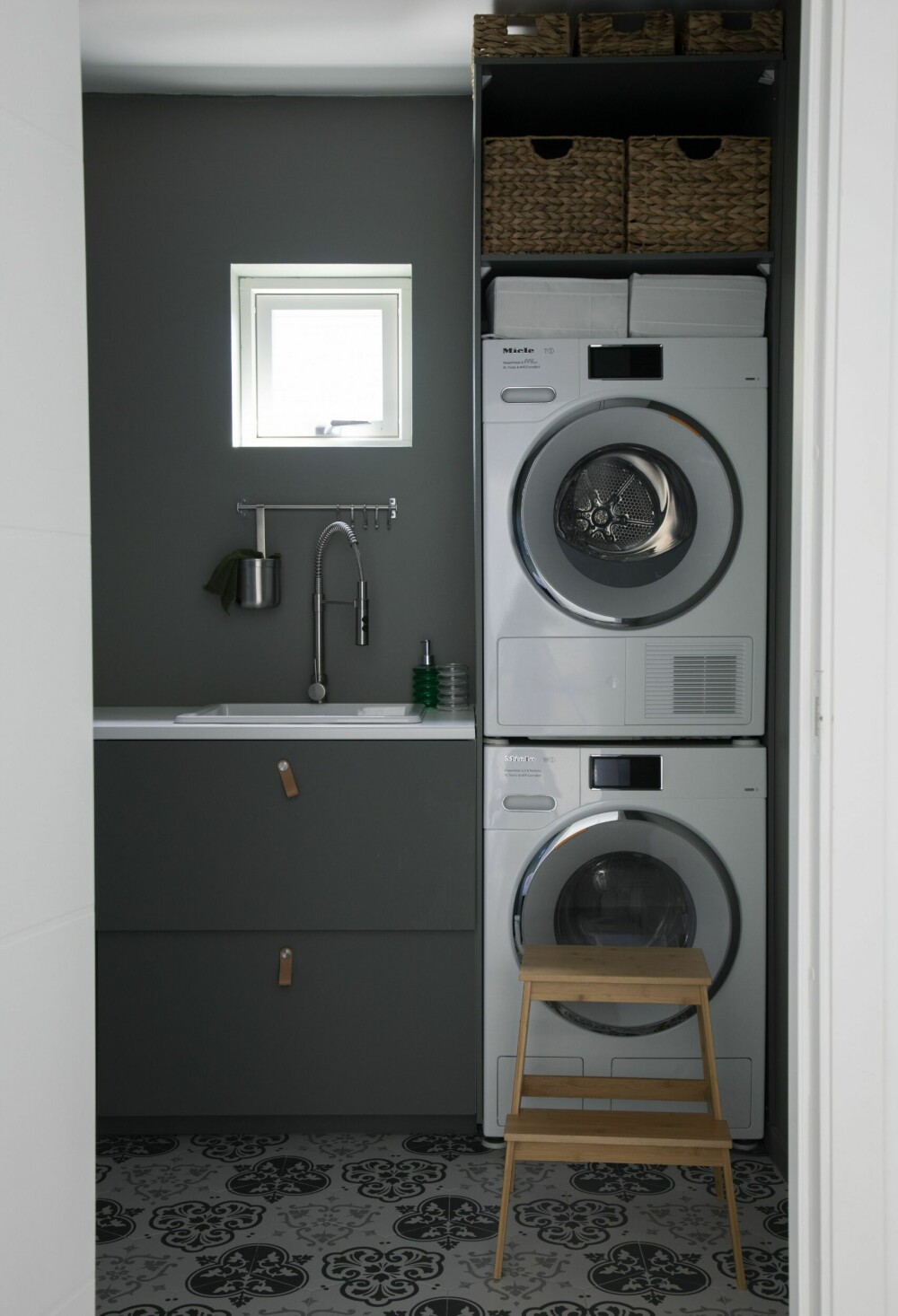 Marsonas tips er å legge vaskerommet til den etasjen der man oppholder seg mest – det gjør det enklere å få klesvasken unnagjort. Hun har gjort vaskerommet til et lunt og hyggelig sted å oppholde seg, med marokkanske gulvfliser fra Fagflis og mørkegrønne vegger tilpasset innredningen fra Ikea. Vaskemaskinen og tørketrommelen kommer fra Miele, mens den praktiske trekrakken er fra Ikea.            