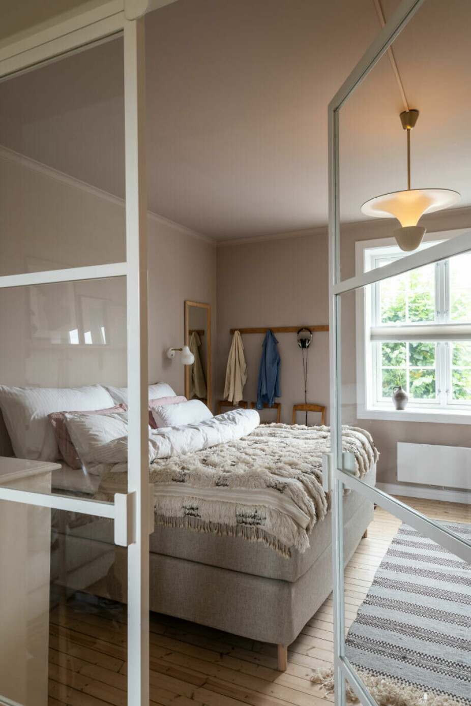 I denne leiligheten leder doble, hvitsprossede glassdører inn fra stuen til soverommet. Slik blir begge rom forsynt med gjennomlys..