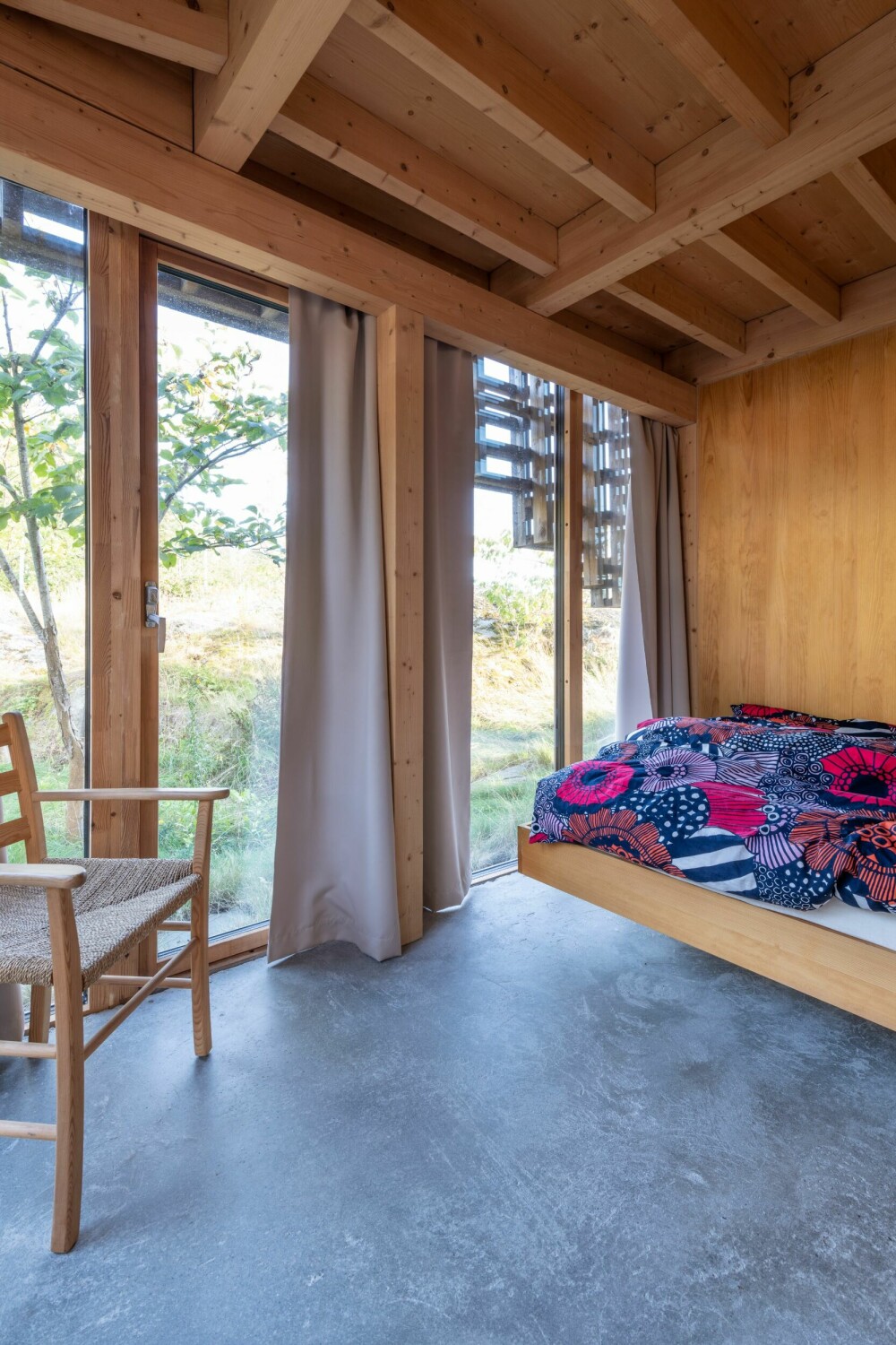 SOVEROM: Også på soverommet er man i nær kontakt med naturen utenfor, takket være glasspanelene som strekker seg fra gulv til tak. Sengetøyet er fra Marimekko.
