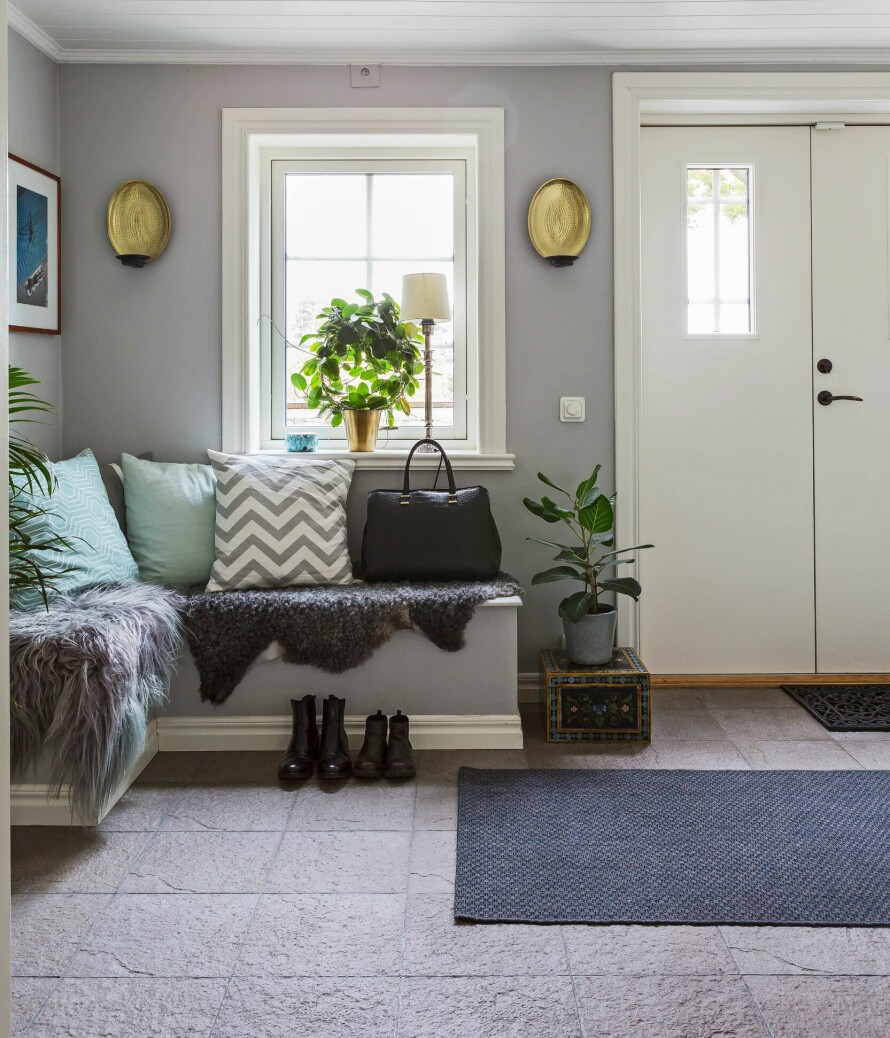 SMART OPPBEVARING: I entreen har Leo laget praktiske plassbygde benker med mye plass til oppbevaring. Puter fra H&M Home, lampetter og teppe fra Ikea. Bilder fra Yellow Korner. Messingkrukke, lampe i vinduet, potten og blomsten fra Blomsterlandet.