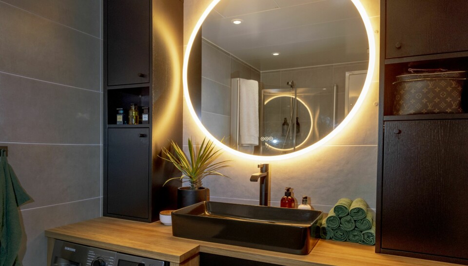 BAD: Badet er nyoppusset, med samme mørke tråd som går gjennom hele leiligheten. LED-lys rundt speilet gir rommet ekstra belysning.