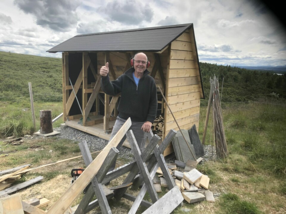 STRØMSPARING: Svein Ringstad snekrer vedskjulet. Solcellene er festet på baksiden av taket og vendt slik at de får mest mulig sol på seg.
