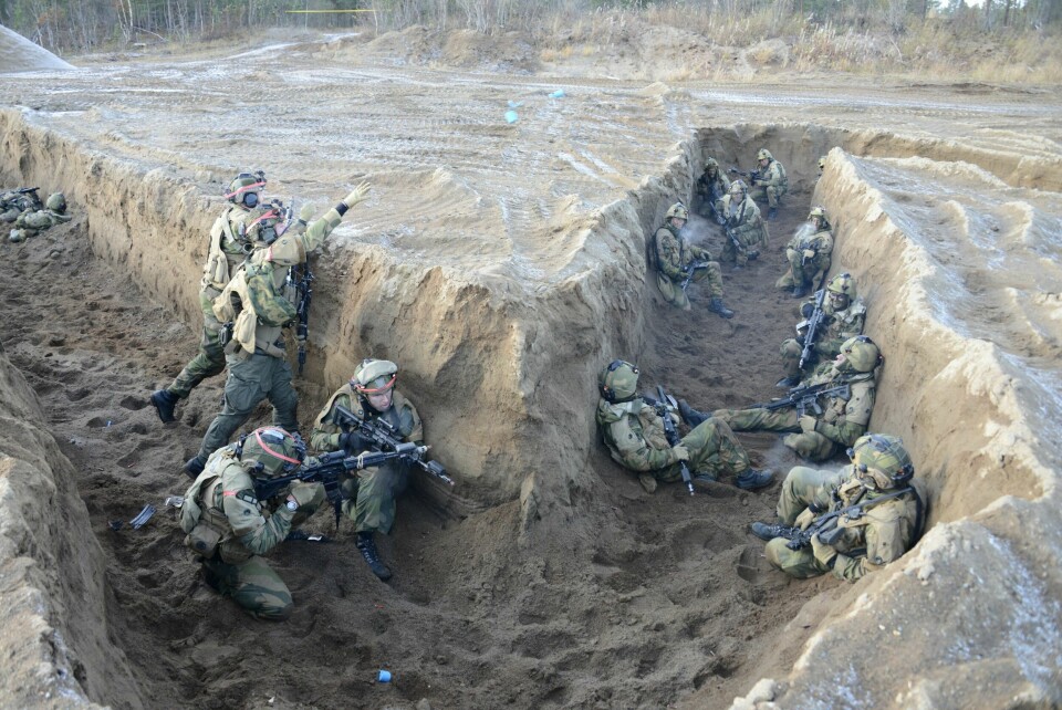 NÆRKAMP VED KNEKKPUNKT: Inntrengerne med rød teip på hjelmene kaster to granater mot soldatene som forsvarer stillingssystemet.