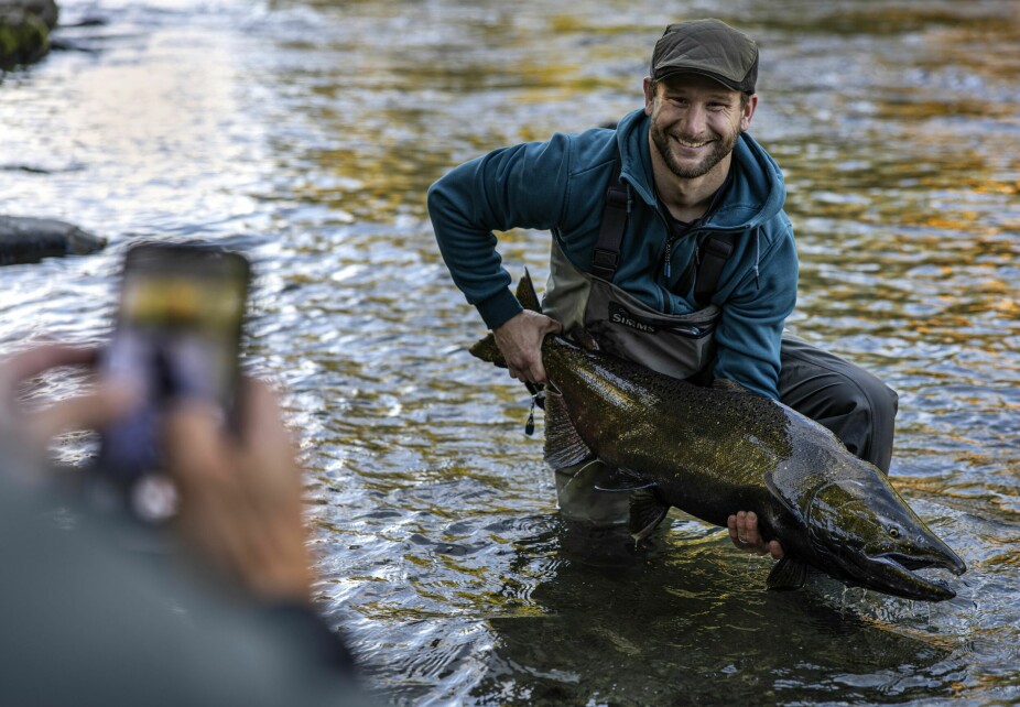 HILSEN HJEM: Britiske Matthew Wooff poserer med en nylig fanget kongelaks. Fire-fem foto med mobilen, så han har noe å vise kona, deretter ble fisken sluppet tilbake ut i elven.