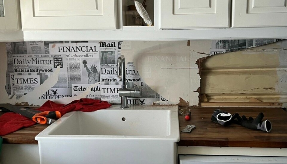 LAG PÅ LAG: Mellom kjøkkenbenken og overskapene var det en glassplate med tapet bak. Platen måtte knuses for å fjernes. Bak tapetet dukket gamle 90-tallsfliser opp, og under enda et lag fant Vibecke den opprinnelige tømmerveggen.