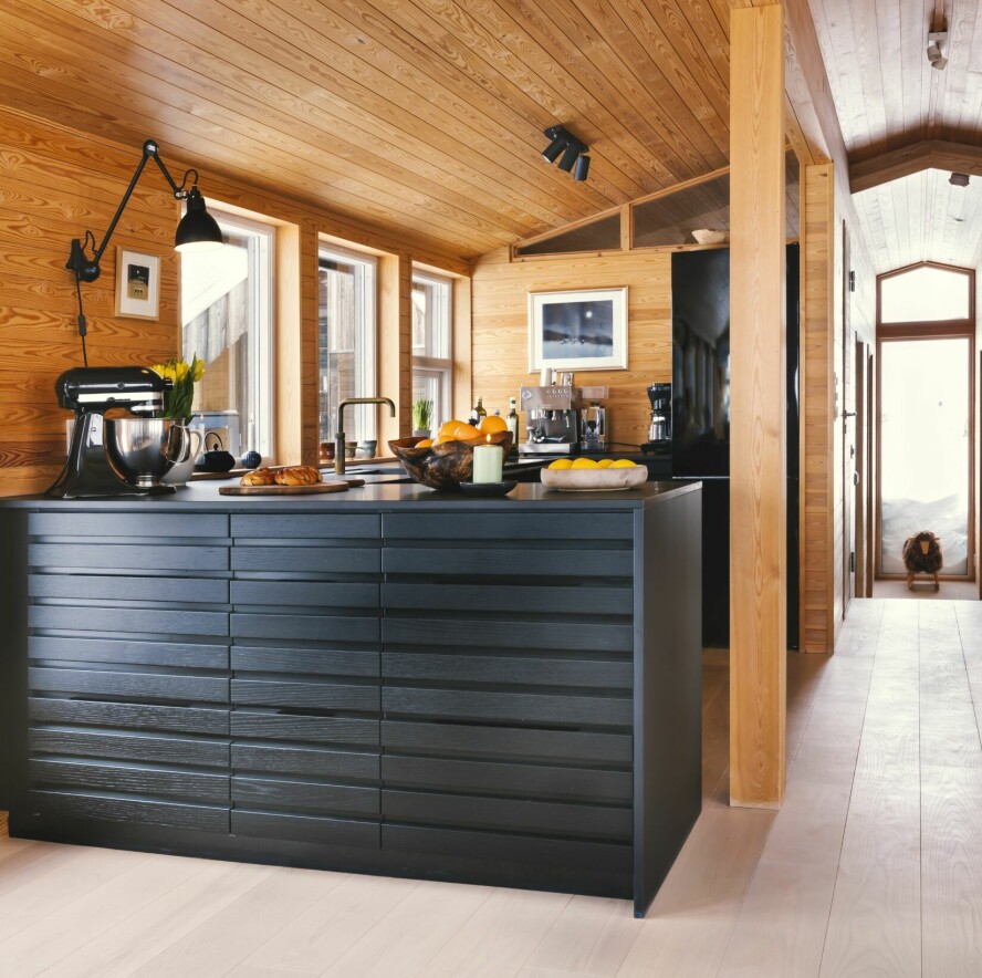 ÅPEN LØSNING: Kjøkkenøya i mørkt tre er en tøff kontrast i det lyse allrommet. De har også valgt bort overskap, noe som forsterker det luftige uttrykket.