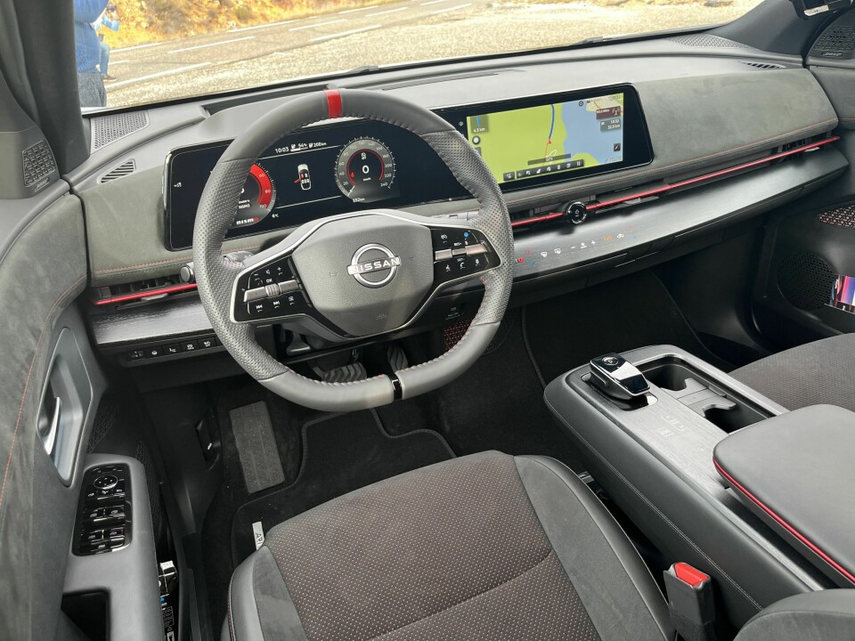 OSER KVALITET: Nissan har vært flinke med materialkvaliteten i Aryia, og det er enda finere i Nismo-versjonen. Røde detaljer og paneler kledd med semsket kunstskinn. Hele midtkonsollen kan skyves frem og tilbake elektronisk og har et stort oppbevaringsrom. Et praktisk brett kan skyves ut fra midtkonsollen om du trenger plass til PC-en mens du lader.