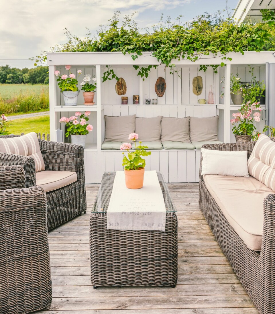 FLERBRUKSMØBEL: Leveggen er bygget med sittebenk og oppbevaring. En uttrekkbar leskjerm brukes når det plutselig begynner å regne. Bak leveggen er det plantet klematis, som klatrer langs veggen til taket. Den sørger for at konstruksjonen dempes og blir en naturlig del av hagen.