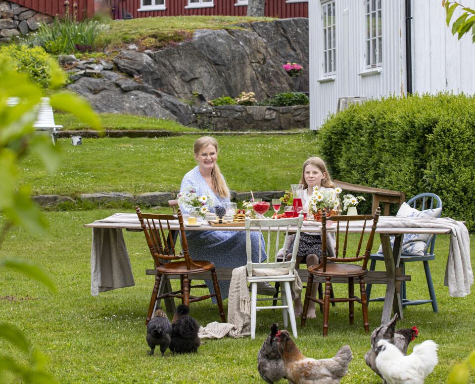 STOR HAGE: Familien har en stor hage, som de gjerne tilbyr flere å bruke. I dag har de bært ut et stort, gammelt bord og noen pinnestoler. Karen Marie har stekt sveler og rørt jordbær. Hønene tripper fornøyd rundt og spiser svelerester.