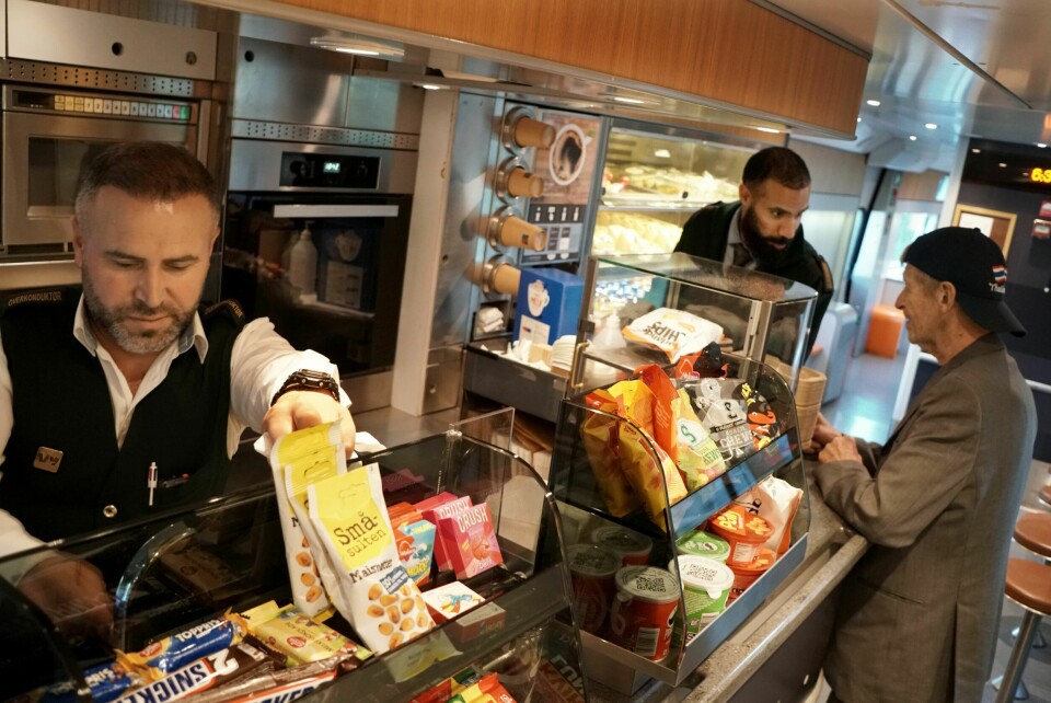 NY DAG VENTER: Overkonduktør Mustafa Bedrihan (t.v.) kasserer seks pølser som har rotert på pølsestekeren gjennom natten. Den langveisfarende får kaffe på vei ut av kafévognen av overkonduktør Alexander Falstad. Store deler av forsinkelsen fra natten er kjørt inn. Et Bergen i sol venter.