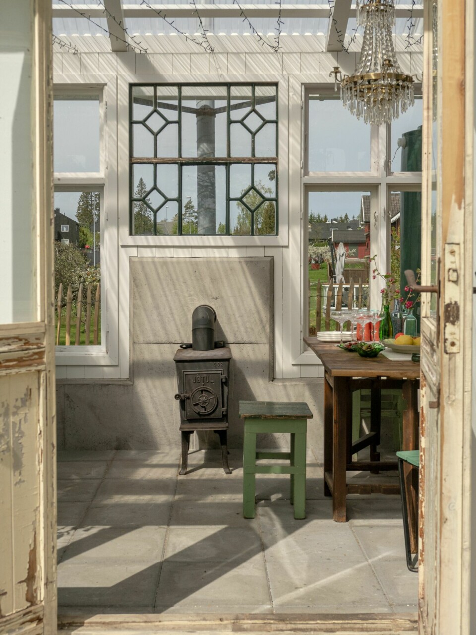 PERSONLIG: De dekorative, gamle vinduene gir drivhuset et helt unikt uttrykk. Ovnen med pipe sørger for at de kan bruke huset bygget hele året. Lysekronen har de fått fra Linns far som er en like opptatt av å samle på ting med historie som paret.