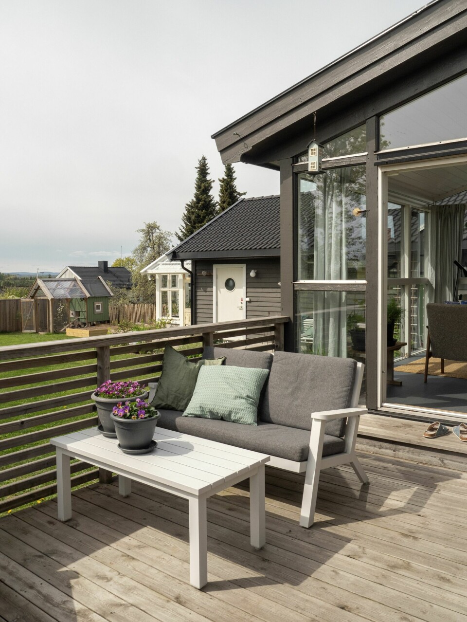 FORLENGELSE AV STUEN: Terrassen brukes mye. Deler er overbygd med et lite tak som gjør at det er fint å sitte ute selv om det regner. En blåregn har tidligere slynget seg oppover taket, men den døde i vinter. Nå har Linn plantet en herdigere sort, 'Blue Moon', som er herdig opp til H5 og krysser fingrene for at den skal bli stor og frodig. Hun har også plantet en villkarifol 'Serotina' inntill rekkverket. – Den har en nydelig duft. Jeg gleder meg til å lukte på den hver gang jeg går i trappen!