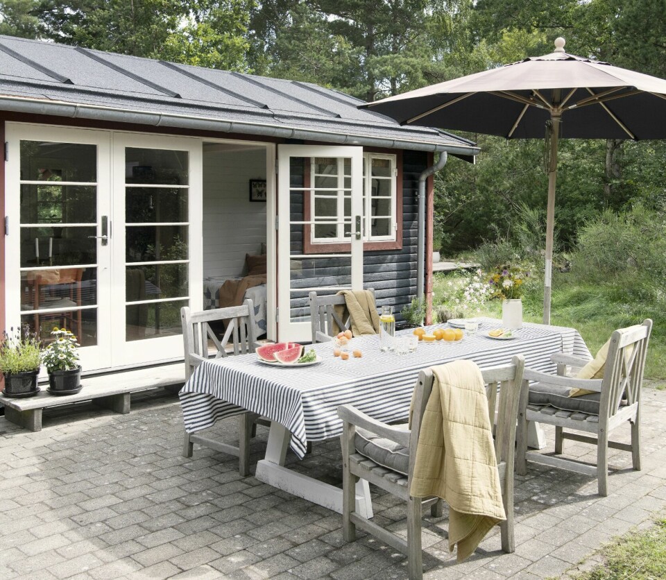SELVBYGGET OG GJENNOMFØRT: Frantz har selv bygget det lange bordet, som står som et samlingspunkt midt på terrassen. Duken plukker opp igjen den «røde» tråden med striper, som går igjen i hele huset.