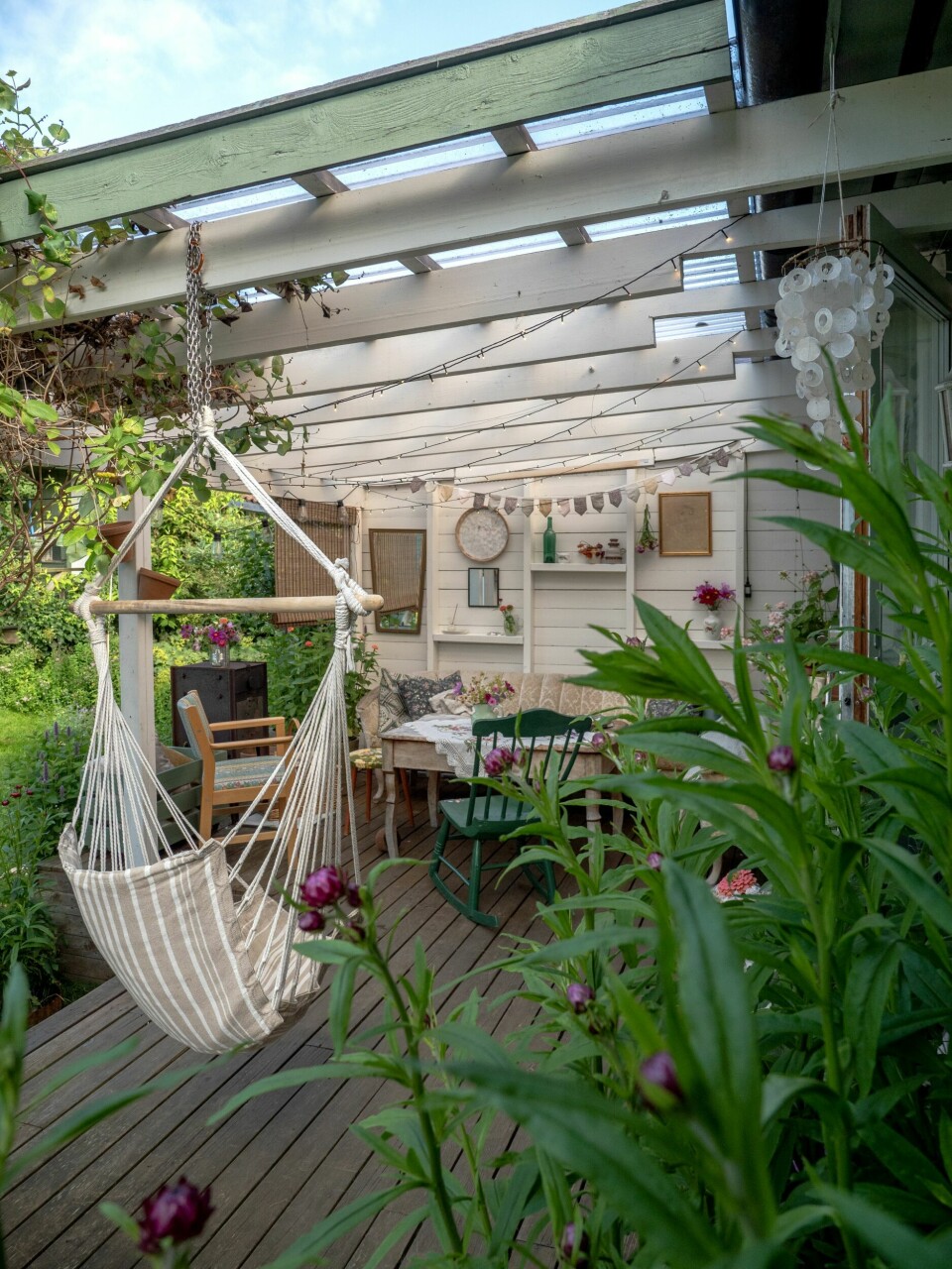 OVERBYGD VERANDA: Her er det deilig å dingle i hengestolen, mens kaffekoppen og blomsterpraten aldri er langt unna.