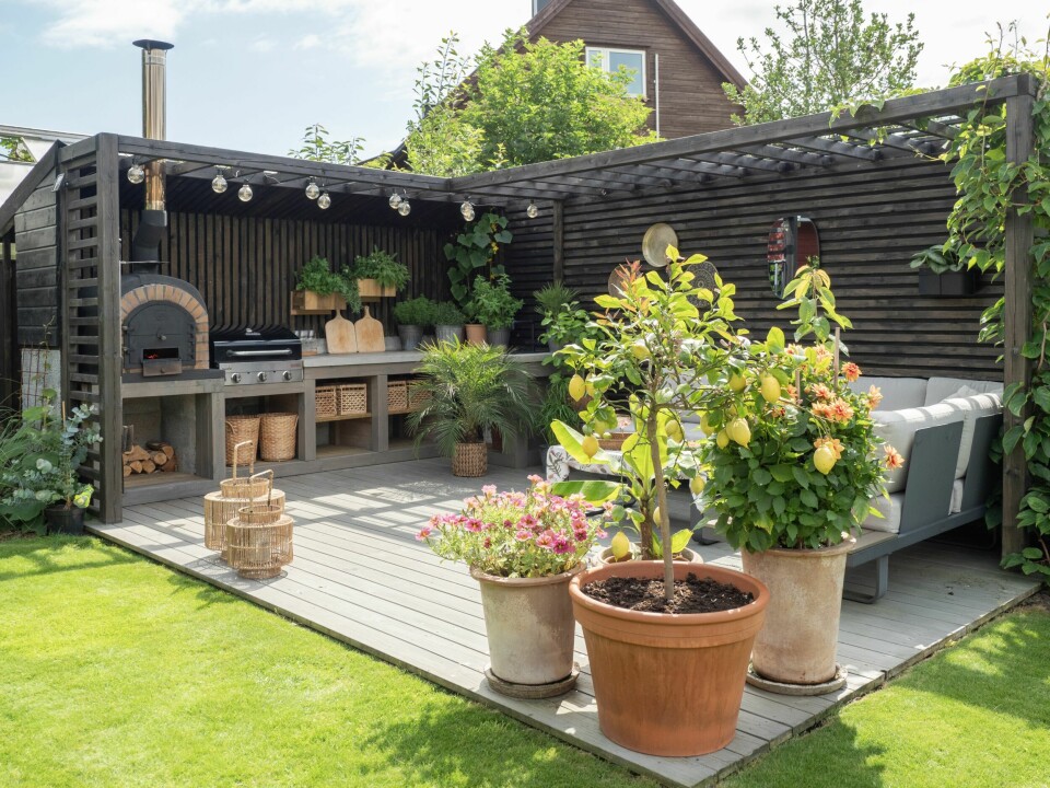 MODNE SITRONER OG NYSTEKT PIZZA: – Vi falt begge pladask for det italienske utseendet på pizzaovnen fra Forno. Utekjøkkenet er designet med utgangspunkt i ovnen med en ramme av 4 x 4 bjelker og en pergola beiset i dempet sort. Vi ønsket at bjelkene skulle være synlige og har derfor valgt å ha åpne hyller istedenfor dører med kurver til oppbevaring.