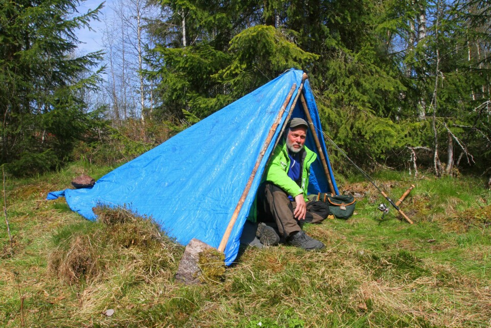 IMPROVISASJON: Her er en enkel måte å skape seg krypinn på. En langsgående stokk er støttet opp med to mindre stokker i omvendt V-form ved inngangen. Stokkene er bundet sammen med tynn, sterk snor. Over takstokken er det lagt en presenning, som er sikret i sidene med et par steiner og stokker.