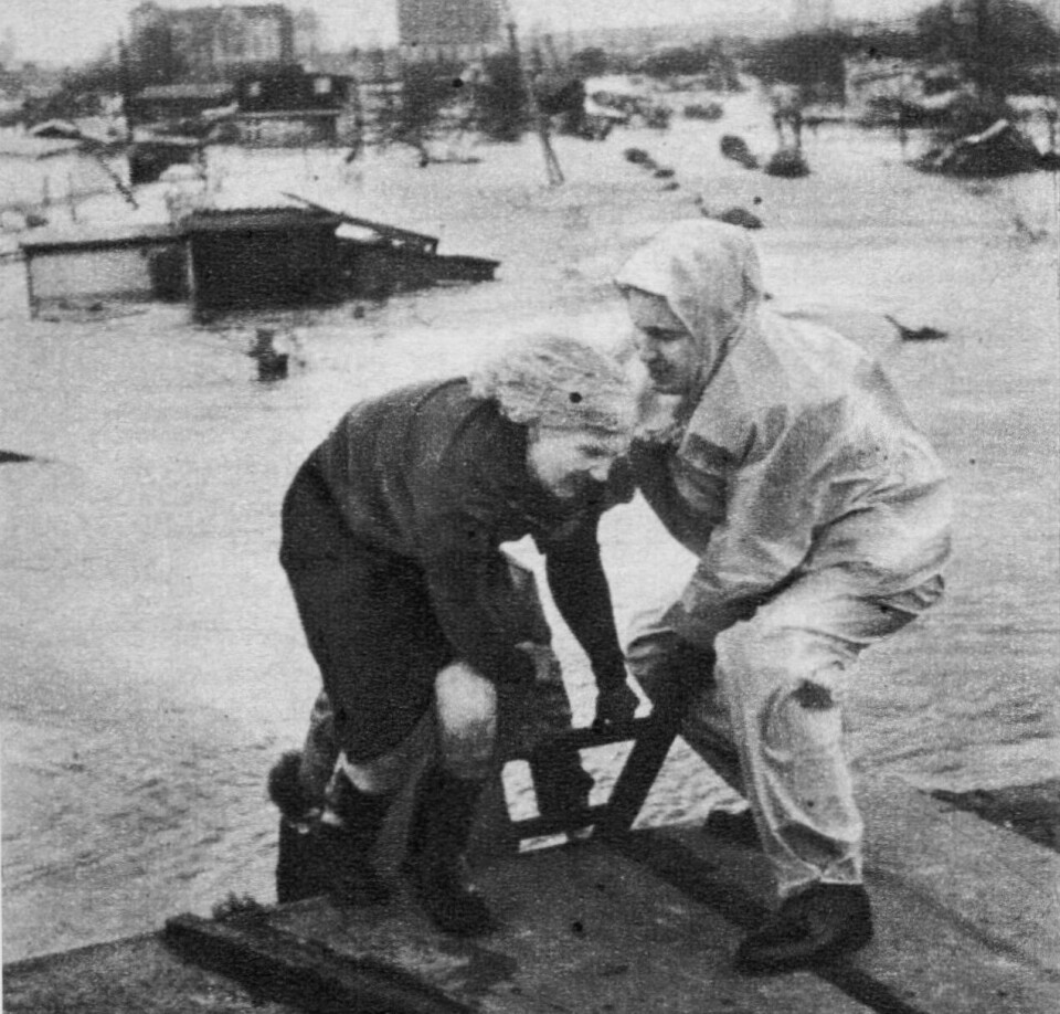 I SIKKERHET: Et medlem av redningskorpset hjelper nødstedte hamburgere opp på et hustak, hvor de foreløpig er i sikkerhet.