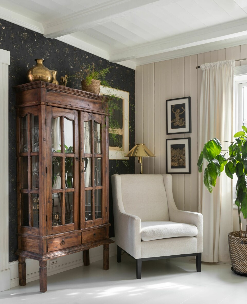 TAPET: Den ene stueveggen har fått mørk tapet. Vitrineskapet er kjøpt brukt, mens stolen er fra Fagmøbler.