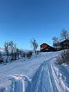 Snødekt turisthytte i tidligere internatskole med skispor og fjell i bakgrunnen
