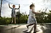 To barn i sommerkjoler hopper og leker på en trampoline utendørs