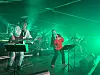 Band opptrer på innendørs scene med grønn belysning og vokalist i front