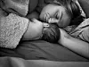 Mor som sover på siden med nyfødt baby inntil brystet i sengen