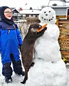 Barn og oter ved snømann i snødekket hage