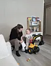 Voksen og lite barn leker med leker på gulvet i et lyst rom