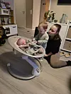 Voksen og småbarn ved babystol i lys stue