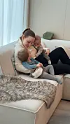 Kvinne sitter i sofa og holder to små barn i en lys stue