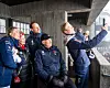 Gruppe mennesker i vinterklær tar en selfie på en betongtribune