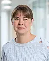 Porträtt av kvinna i ljus stickad tröja i en ljus kontorskorridor.
