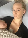 Nicole Ryle ligger ned med sovende spædbarn på brystet og ser træt ind i kameraet.